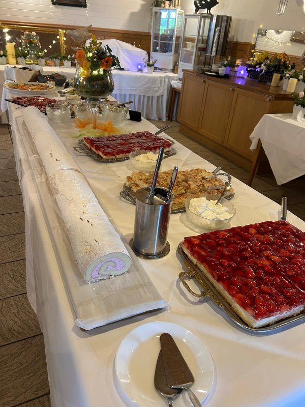 Kuchenbuffet mit Erdbeertorte, Butterkuchen und Biskuitrolle auf weiß gedeckter Tafel