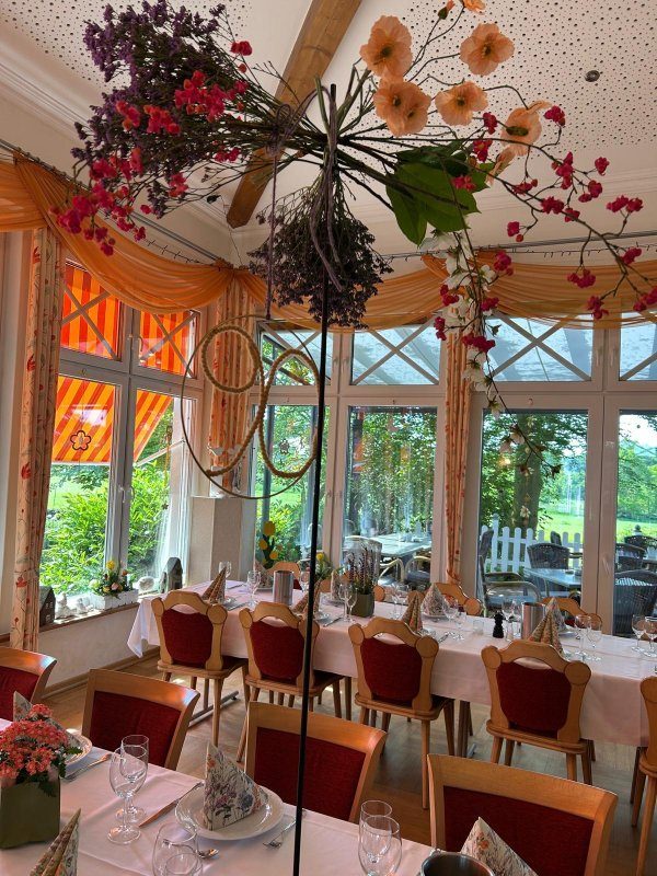 Festlich eingedeckte Tafel im Wintergarten mit Blumendekoration und Blick ins Grüne